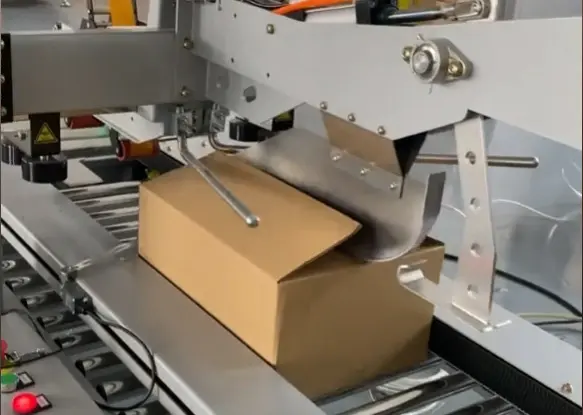 The-two-top-flaps-are-folded-inward-by-angled-metal-guides